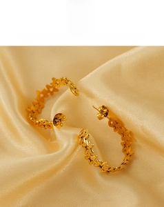 Detailed view of polished gold star-shaped hoop earrings on elegant silk fabric background