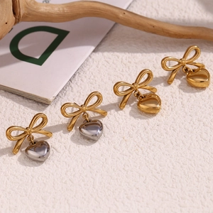 Détail des boucles d'oreilles nœud papillon et cœur en or et argent sur fond texturé