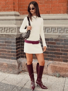 Slim fit white ribbed knit long sleeve mini dress styled with boots and belt in street view
