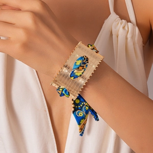 Detailed macro of gold metal cuff bracelet with colorful silk scarf fabric inlay