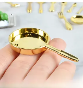 Close-up of a miniature golden frying pan model held by hand for dollhouse kitchen decor