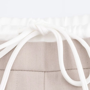 Close-up of khaki and white patchwork drawstring elastic waistband on woven wide leg pants