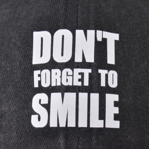 Black washed cotton baseball cap with Don't Forget To Smile white printed text