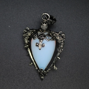 Macro shot of silver winged pendant with white teardrop stone and pentagram on black surface