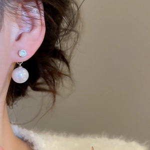 Close-up of vintage silver pearl earrings with zircon stud on woman's ear