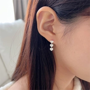 Detail shot of triple silver heart earrings featuring engraved letters on 925 silver