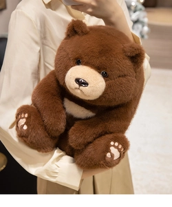 Detailed view of plush teddy bear with embroidered paw prints and crescent chest patch