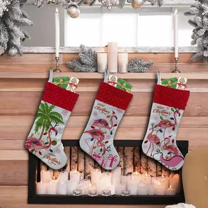 Three white Christmas stockings with red cuffs featuring flamingo and palm tree patterns