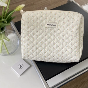 Close-up of quilted cotton cosmetic bag with floral print and The Jolly House label