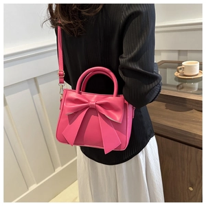 Borsa a mano rosa con grande fiocco decorativo mostrata in un ambiente café