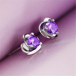 Macro shot of purple gemstone stud earrings with silver heart-shaped metal setting