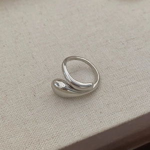Macro detail of silver drop-shaped ring with polished mirror finish on linen surface