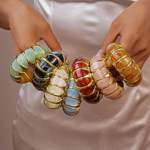 Macro detail of acrylic resin bangles with gold metal frames in various colors