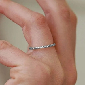 Dettaglio di un anello a sfere d'argento minimalista indossato al dito con trama elegante