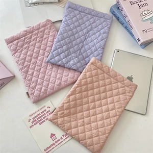 Close-up of three quilted laptop sleeves in pastel colors with diamond stitching detail