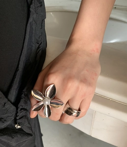 Detail view of a hollow flower ring with white pearl and a wide silver band
