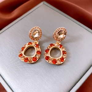 Dettaglio di orecchini a perno vintage dorati con strass ambra e arancio in scatola regalo