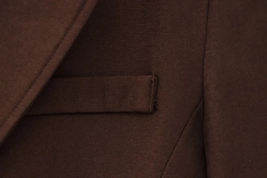 Detail of dark brown twill fabric texture and professional pocket stitching on suit