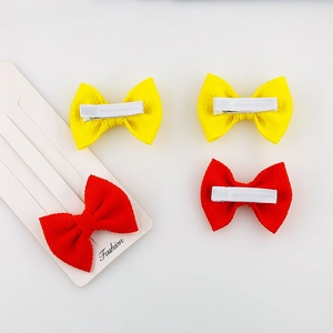 Set of four fabric baby bow hair clips in red and yellow on a white fashion display card