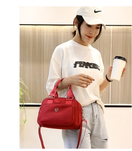 Close-up of red nylon handbag with adjustable strap and front zipper pocket detail
