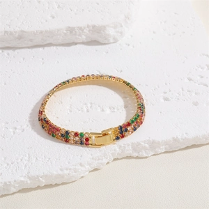 Close-up of triple-row gold bracelet featuring colorful cubic zirconia and folding clasp