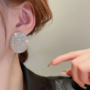 Macro view of geometric round stud earrings with pave-set rhinestones and gold finish