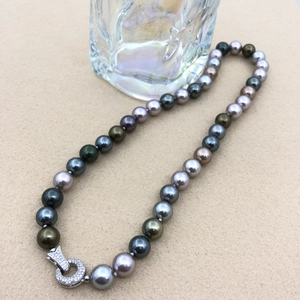 Detail of multi-color Tahitian pearls with a sparkling silver diamond clasp on a necklace