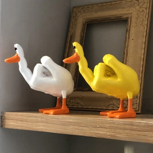 Close-up of funny resin duck figurines with middle finger gesture on a wooden shelf