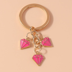 Detailed close-up of golden keychain featuring three pink diamond-shaped enamel pendants