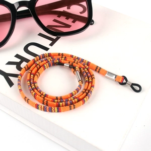 Bohemian style colorful woven eyewear strap with adjustable rubber loops on a book