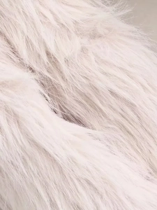 Close-up detail of soft faux fur fabric texture in pale pink and cream white tones