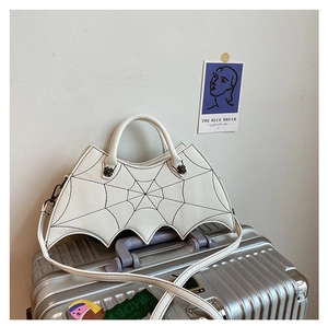 Detailed shot of white bat-wing gothic crossbody bag on a silver suitcase
