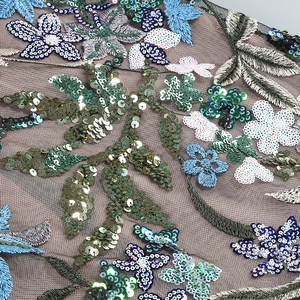 Broderie détaillée avec motifs floraux colorés et paillettes sur le tissu en maille de robe