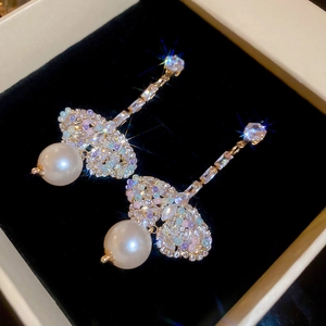 Macro detail of gold butterfly earrings with sparkling crystals and elegant white pearls