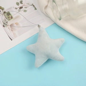 Close-up of light blue plush star charm with silver cord on soft white fabric background