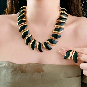 Détail d'un collier feuille vintage doré et d'une bague avec pierre verte