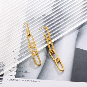 Dettaglio degli orecchini pendenti a catena cubana placcati in oro 18K su sfondo moda