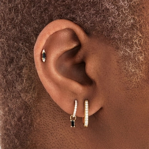Macro shot of 3-piece gold earring set with black gemstones and zircon on model