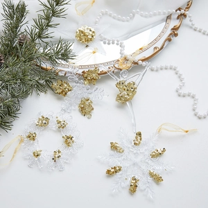 Acrylic Christmas ornaments with gold glitter snowflake and star designs on a white surface