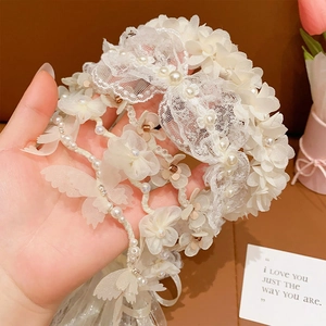 Detail of white lace hairband with delicate pearls and floral butterfly patterns