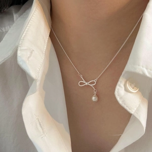 Close-up of a silver bow pearl necklace worn with a white shirt for an elegant look