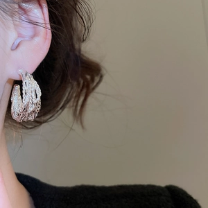 Detail shot of a silver woven texture earring worn by a model with a vintage aesthetic