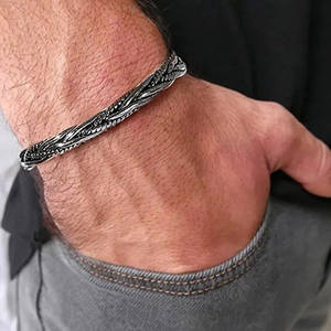 Close-up of vintage Viking braided bangle on male wrist in denim pocket scene
