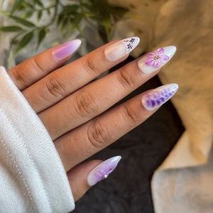 Detail of almond press-on nails with 3D purple flowers and elegant gradient patterns
