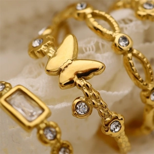 Close-up of golden butterfly ring and inlaid crystal gems on white lace background