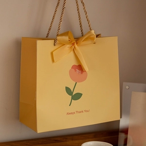 Yellow paper gift bag with tulip floral illustration and matching ribbon bow handle