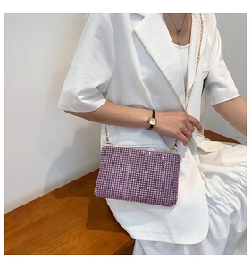 Pink rhinestone shoulder bag with gold metal chain strap shown on a wooden bench