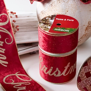 Red velvet Christmas ribbon with gold Merry Christmas print on rustic wood background