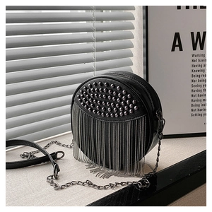 Close-up of black round leather crossbody bag with silver studs and chain fringe