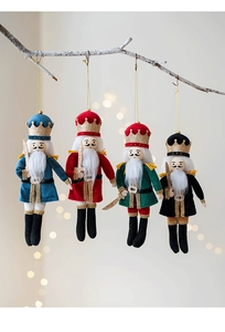 Close-up of four cloth Nutcracker soldier ornaments hanging on a snowy Christmas branch